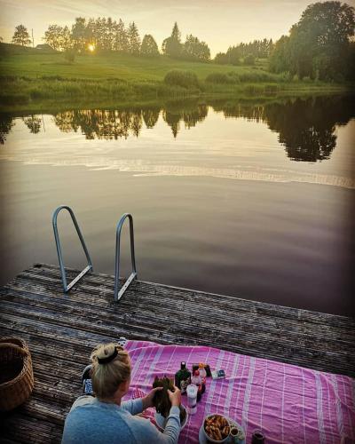 a woman taking a picture of a body of water at Ala Sarise saunamaja in Sarise