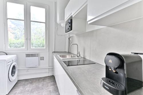 une cuisine avec un évier et une machine à laver dans l'établissement Appartement Vue panoramique sur la capitale - II, à Puteaux