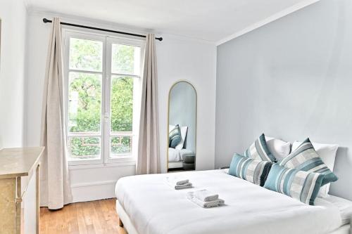 une chambre blanche avec un lit et une fenêtre dans l'établissement Appartement Vue panoramique sur la capitale - II, à Puteaux