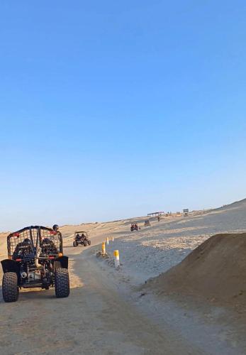 a jeep driving down a dirt road in the desert at Arena Hostal in Paracas