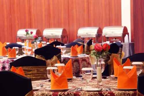 a long table with orange napkins and flowers on it at Grand Hatika Hotel in Tanjungpandan