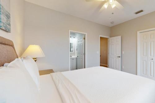 a bedroom with a white bed and a ceiling fan at Sharp Reef on the Gulf #5 in Pensacola