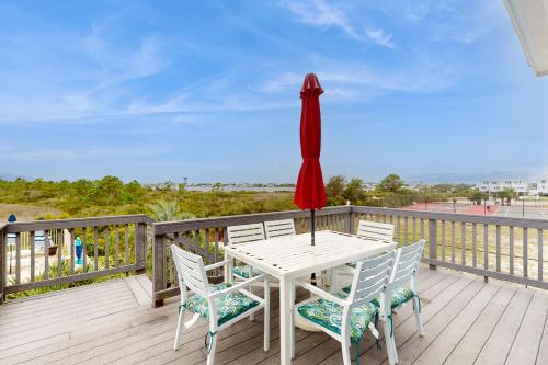 a white table with chairs and a red umbrella on a deck at Sharp Reef on the Gulf #5 in Pensacola