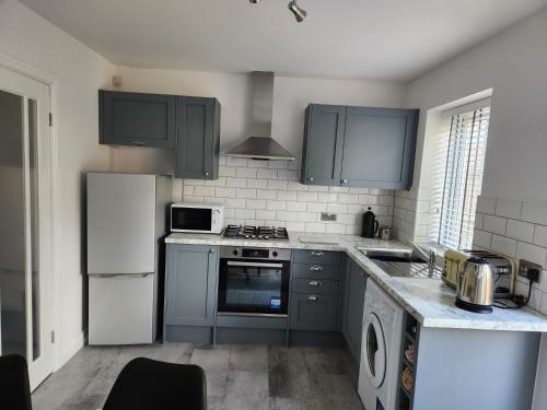 a kitchen with blue cabinets and a stove top oven at Cosy house for business travel and pleasure in Bickershaw