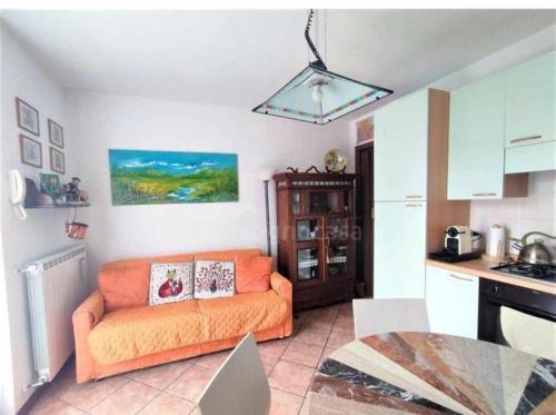 a living room with an orange couch in a kitchen at La casa dei sentieri in Rovetta