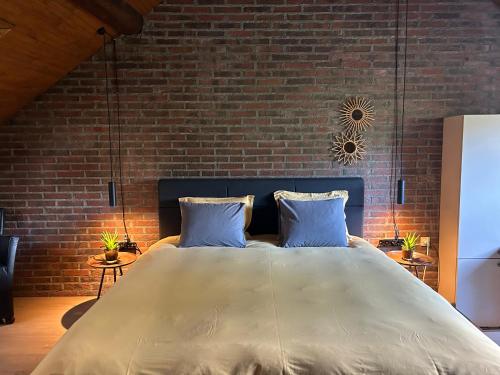 a bedroom with a large bed with a brick wall at Vakantiewoning Hoogveld in Kortessem