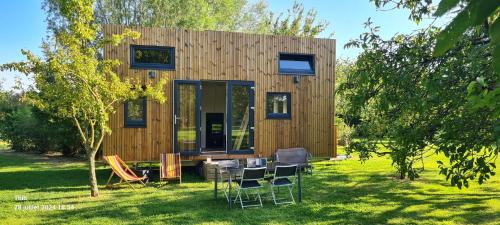 une petite maison avec une table et des chaises dans la cour dans l'établissement Le petit nid des Mésanges, à Volckerinckhove