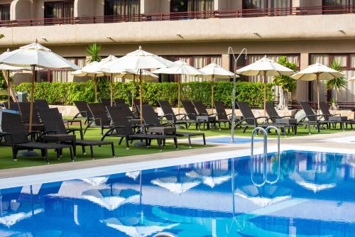 a hotel with a pool and chairs and umbrellas at GF Fañabe in Adeje