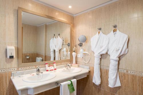 a bathroom with two sinks and a mirror and towels at GF Fañabe in Adeje