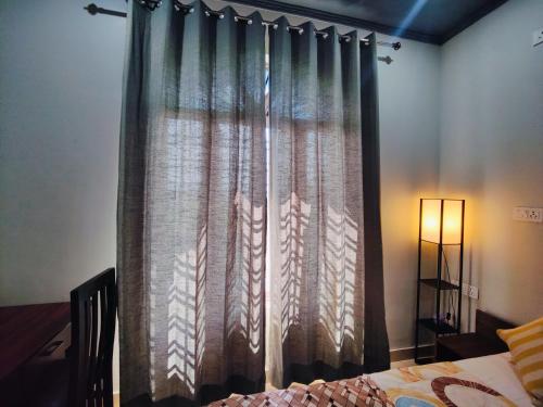 a curtain in a room with a bed and a lamp at Hoztel Jollygrrant Doon in Rāni Pokhri