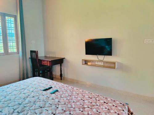 a bedroom with a bed and a desk and a tv on the wall at Hoztel Jollygrrant Doon in Rāni Pokhri