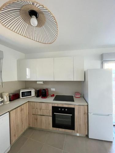 une cuisine avec des armoires blanches et un réfrigérateur blanc dans l'établissement Appartement 2 chambres en rez de jardin avec piscine, à Cogolin