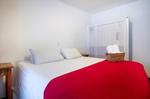 a bedroom with a white bed with a red blanket at VELINN Caravela Pousada Ilhabela in Ilhabela