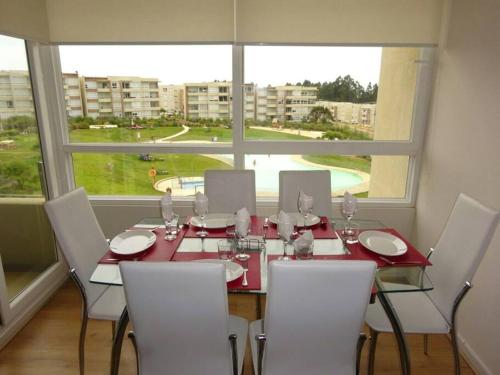 a dining room table with white chairs and a large window at Lomas de Papudo 4 in Agua Salada