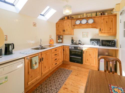 a kitchen with wooden cabinets and a wooden table at Colliers Barn in Ballycastle