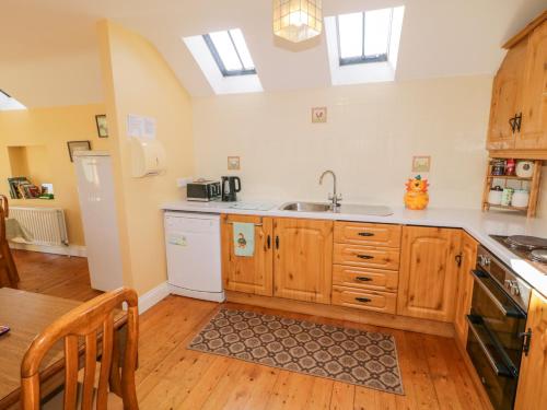 a kitchen with wooden cabinets and a sink at Colliers Barn in Ballycastle