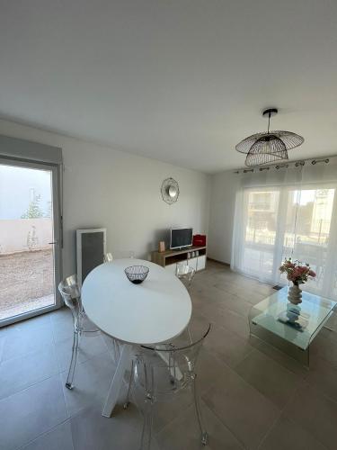 un salon avec une table et des chaises blanches dans l'établissement Appartement 2 chambres en rez de jardin avec piscine, à Cogolin