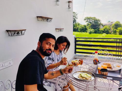 a man and woman sitting at a table eating food at Hoztel Jollygrrant Doon in Rāni Pokhri