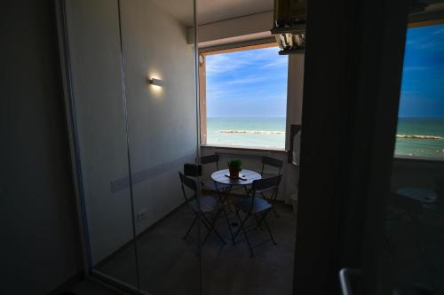 a table and chairs in a room with a view of the ocean at NON DISTA APARTMENT Appartamentino sul mare in Ortona