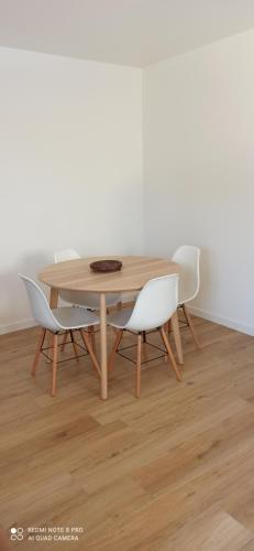 une table en bois entourée de trois chaises blanches dans l'établissement Joli studio à la montagne studio à la montagne, à Les Vigneaux