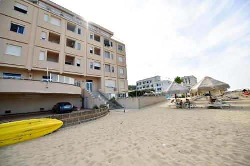 a yellow surfboard on a sandy beach next to a building at NON DISTA APARTMENT Appartamentino sul mare in Ortona