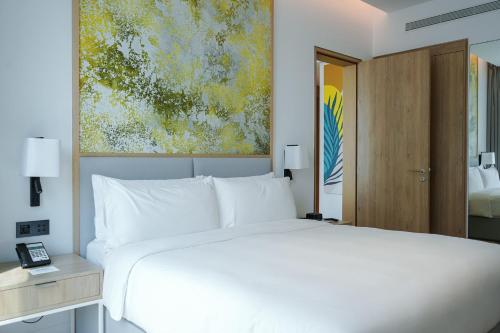 a bedroom with a white bed and a painting at Holiday Inn Dubai Business Bay by IHG in Dubai