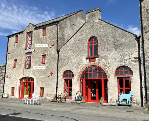 a large stone building with red doors and windows at Riverfront Apartments at The Blue Goat Ramelton in Ramelton