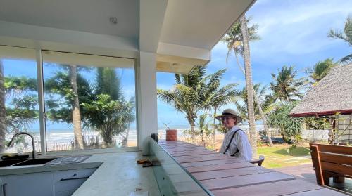 a person standing in a kitchen with a view of the beach at Turtle Beach Club in Pelena