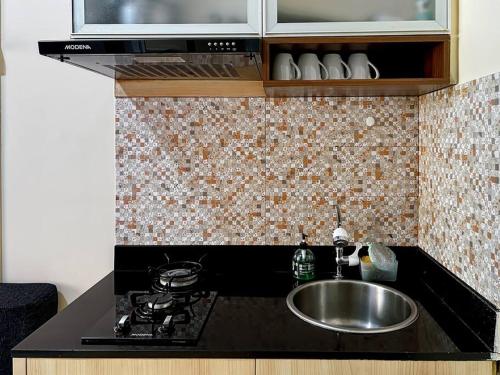 雅加达2BR Apt Green Pramuka with Pool & Wi-Fi by 2ndHome的厨房柜台设有水槽和炉灶。