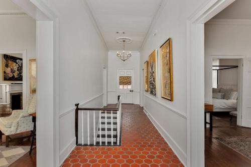 a hallway with white walls and a staircase with a red floor at Wilkins Townhouse - 3 Bed, 3 Bath, Walk to Downtown in Natchez