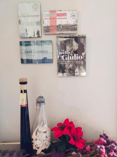 a bottle and flowers on a table with pictures on the wall at L'angolo in Turin