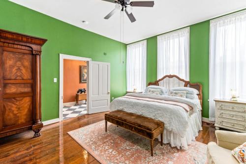 a bedroom with green walls and a bed and a couch at 610 Franklin - 3 Bed, 3 Bath, Duplex, Heart of Downtown in Natchez