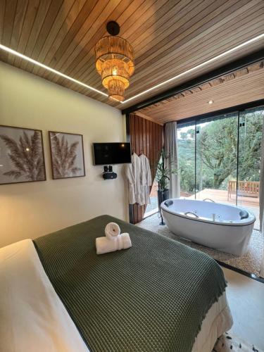 a bedroom with a tub and a bed with a towel at Flor da serra in Urubici