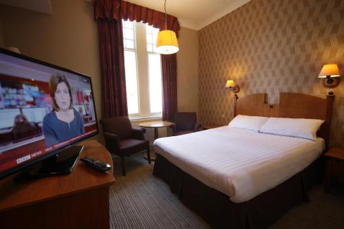 a hotel room with a bed and a flat screen tv at The Angel Hotel in Cardiff