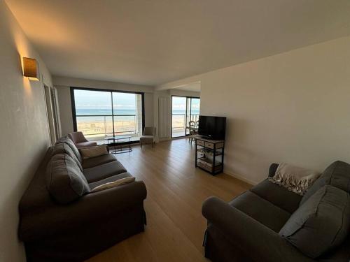 - un salon avec deux canapés et une vue sur l'océan dans l'établissement L Océan à vos Pieds Résidence Ouragan, à Le Touquet-Paris-Plage