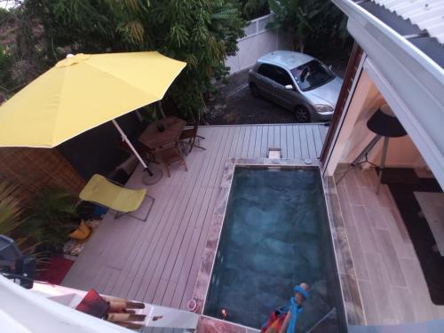 an overhead view of a pool with an umbrella and a car at Hibiscus Paradise in Vieux-Habitants