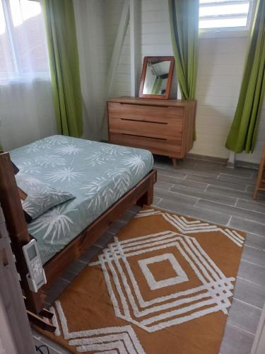 a bedroom with a bed and a mirror and a dresser at Hibiscus Paradise in Vieux-Habitants