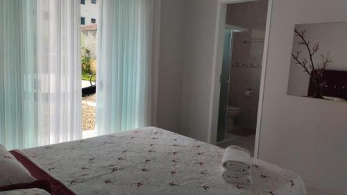 a white bedroom with a bed and a window at Suítes Garden in Pomerode
