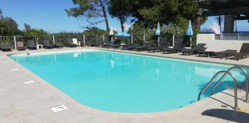 ein großer blauer Pool mit Stühlen um ihn herum in der Unterkunft Les pieds dans l'eau in San-Nicolao