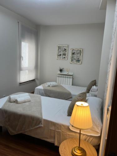 two beds in a room with a table with a lamp at Avanza 4 Plaza Galicia in Sarria