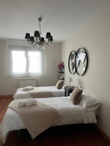 a bedroom with two beds and a chandelier at Avanza 4 Plaza Galicia in Sarria