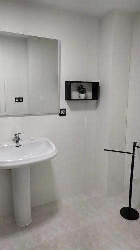 a white bathroom with a sink and a mirror at Apartamento cerca del centro con parking gratuito in Castellón de la Plana