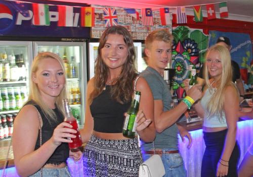 a group of people standing in a bar holding drinks at Backpackers In Paradise Under 45's Hostel in Gold Coast