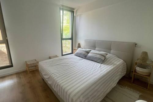 - une chambre blanche avec un grand lit et 2 oreillers dans l'établissement Sérénité Raphaëloise, à Valescure