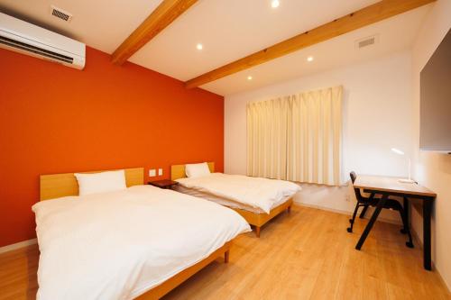 two beds in a room with orange walls at KAIBENBETSU NAGATO MISUMI - Vacation STAY 01643v in Nagato