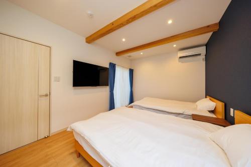 two beds in a bedroom with a tv on the wall at KAIBENBETSU NAGATO MISUMI - Vacation STAY 01952v in Nagato
