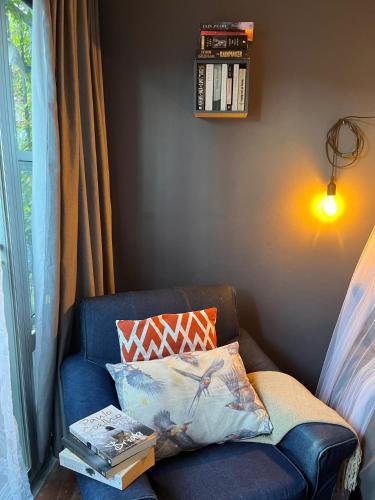 a blue couch with a pillow and a book at Seaside Getaway @ Swallow House Suite #1 in Cape Town