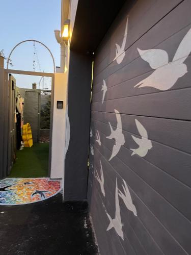 a wall with white birds painted on it at Seaside Getaway @ Swallow House Suite #1 in Cape Town
