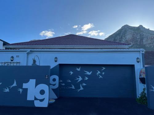 a house with a blue garage door with birds on it at Seaside Getaway @ Swallow House Suite #1 in Cape Town