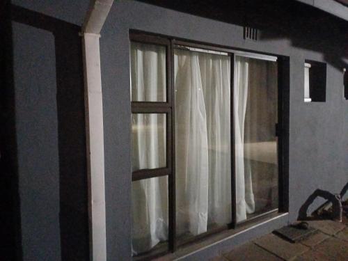 a window with white curtains in a room at Willow Guest house in Vereeniging